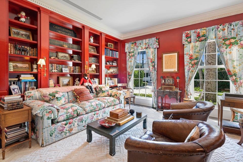 The library features stippled walls in dark cherry, a gas fireplace with a marble mantel and built-in bookshelves.