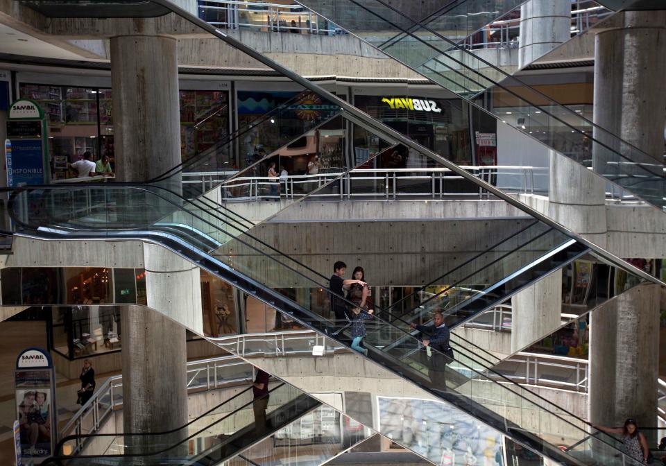In this April 10, 2014 photo, people ride the nearly empty escalators inside Sambil mall in the city in Caracas, Venezuela. Fifteen years of socialist rule and an acute economic crisis is catching up with Venezuela’s shopping malls, once impenetrable oases of consumerism where rich and poor alike sought refuge from crime-ridden streets. (AP Photo/Fernando Llano)