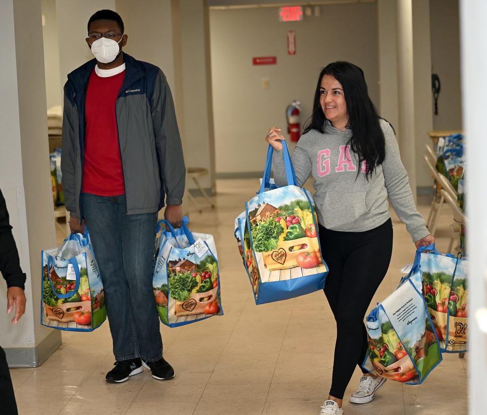 DoorDash driver Ginna Ramirez, right, carries bags of food for families in need from the Greater Framingham Community Church as part of the Project DASH program on Oct. 8. At left is Caleb Hyman of the church.