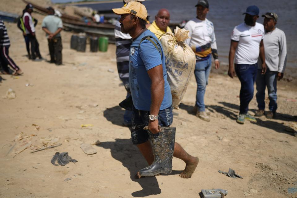 A miner carries his belongings after arriving by boat from the Bulla Loca mine, in La Paragua, Bolivar state, Venezuela, Thursday, Feb. 22, 2024. The collapse of the illegally operated Bulla Loca open-pit gold mine in central Venezuela killed at least 14 people and injured several more, state authorities said Wednesday, as some other officials reported an undetermined number of people could be trapped. (AP Photo/Ariana Cubillos)