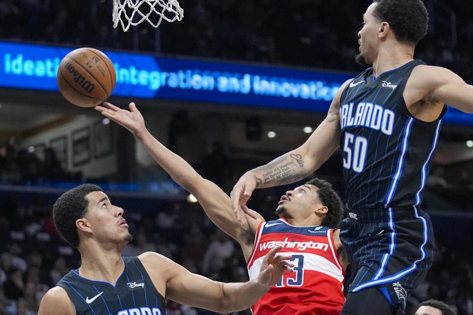 Washington Wizards guard Jordan Poole (13) shoots between Orlando Magic guards Caleb Houstan, left, and Cole Anthony during the first half of an NBA basketball game Wednesday, March 6, 2024, in Washington. (AP Photo/Alex Brandon)