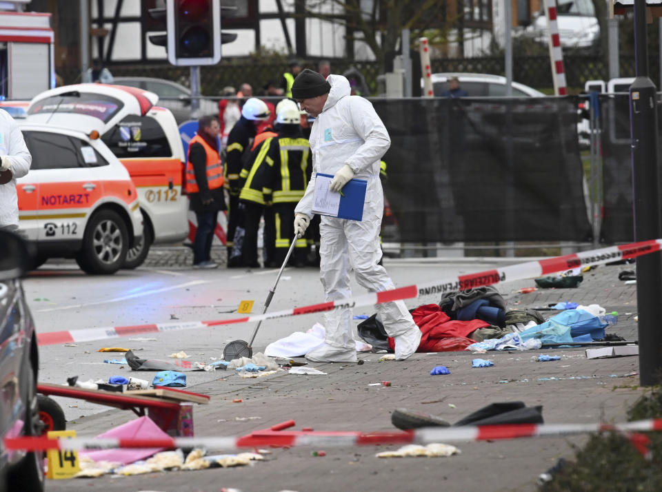 Police and rescue workers stand next to the scene of the accident with a car that is said to have crashed into a carnival parade in Volkmarsen, central Germany, Monday, Feb. 24, 2020. Several people have been injured, according to the police. The driver had been arrested by the police. (Uwe Zucchi/dpa via AP)