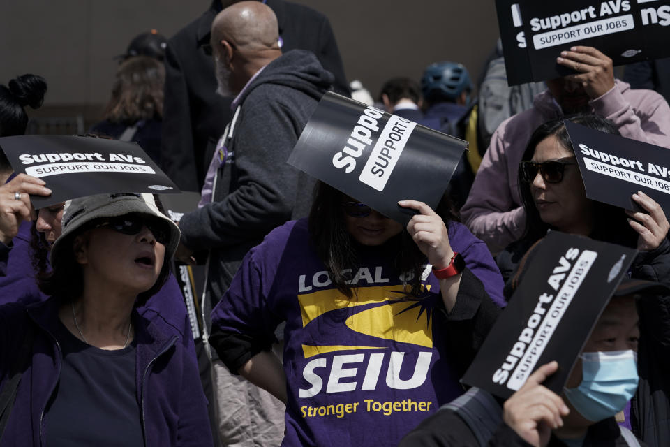 People hold up signs in support of a proposed robotaxi expansion as they wait to enter the Public Utilities Commission building on Thursday, Aug. 10, 2023, in San Francisco. (AP Photo/Godofredo A. Vásquez)