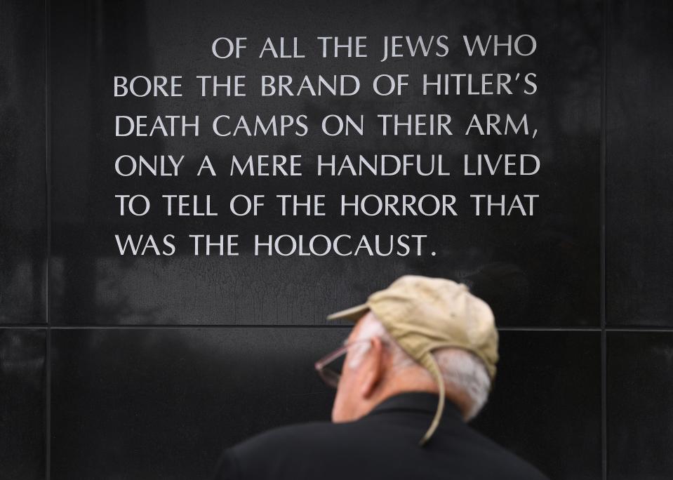 A man sits beside a memorial dedicated to victims of the Nazi terror, during the Yom Hashoah Commemoration event which honors the memories of the victims and survivors of the Holocaust, in Los Angeles on April 28, 2019.