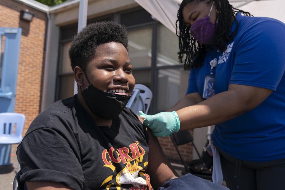 Christopher Fitzhugh, 13, of Washington, laughs in relief that his shot didn't hurt, as Leah Napier, a certified clinical medical assistant, completes his Pfizer COVID-19 vaccine, Wednesday, May 19, 2021, at a clinic held by Community of Hope, a community health organization, at the Washington School for Girls in southeast Washington. Several schools sent information about the vaccine drive to their students' families to ensure access to the vaccine, newly approved for children ages 12-15. "I wanted to get it out of the way," says Fitzhugh, "I'm not trying to get COVID and I'm trying to get vaccinated so I can see my friends." (AP Photo/Jacquelyn Martin)