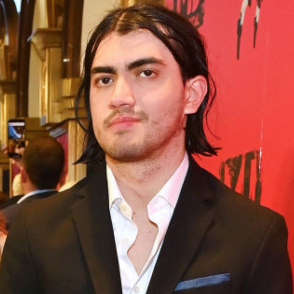 Man in a black suit without a tie on a red carpet