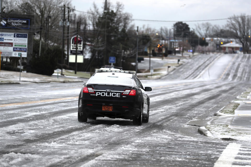 A Town of Swansboro police officer patrols iced covered Hwy 124 after a winter storm hit North Carolina in Swansboro, N.C., on Saturday, Jan. 22, 2022. A layer of ice and a blanket of snow has covered coastal areas stretching from South Carolina to Virginia. The winter weather system that entered the region on Friday brought colder temperatures and precipitation not often seen in the region. (AP Photo/Tom Copeland)