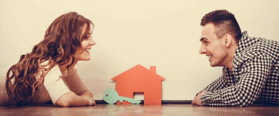 real estate, family and couple concept - smiling couple lying on floor with symbol house and key daydreaming at home, vintage filter