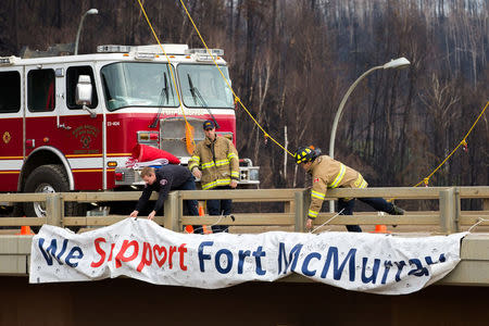Fort McMurray firefighters fix a sign that reads "We Support Fort McMurray" on an overpass above Memorial Dr. in Fort McMurray, Alberta, Canada June 1, 2016. REUTERS/Topher Seguin