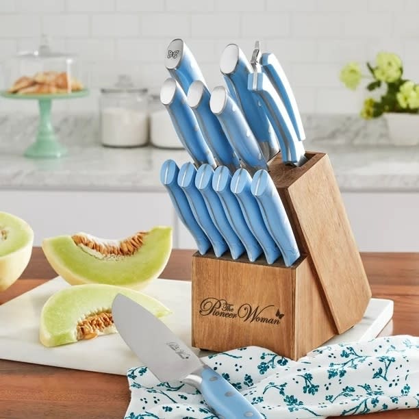 knife block with blue knives on a cutting board with pieces of melon on it