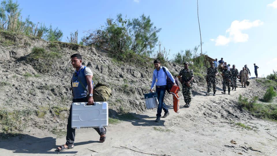 Election officials carry Electronic Voting Machines (EVM) and other election material, followed by paramilitary personnel, in Lohore Sapori, Assam on April 10, 2019. - Biju Boro/AFP/Getty Images