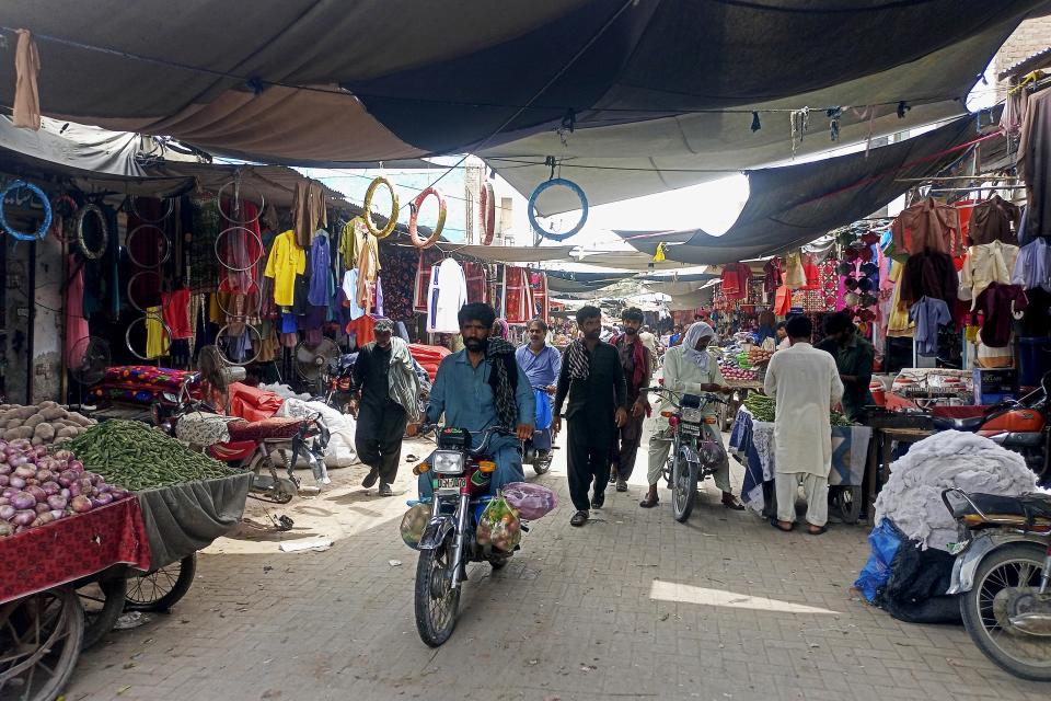 People visit a market to buy groceries and other items in Rojhan town, in Rajanpur, a district of Pakistan's Punjab province, Tuesday, May 23, 2023. Punjab is Pakistan’s biggest agricultural producer and its most populated province. (AP Photo/Asim Tanveer)