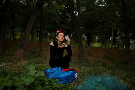 Chinese performance artist Han Bing applies paint to his face before a shoot with German photographer Katharina Hesse at the outskirts of Beijing, China, October 2, 2017. REUTERS/Thomas Peter