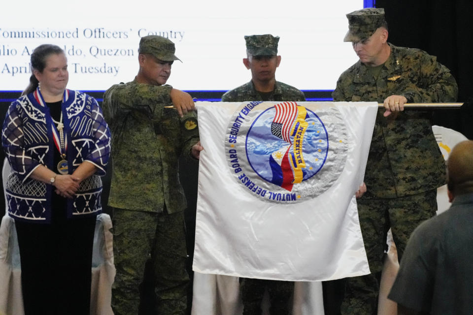 U.S. Marine Corps MGEN Eric Austin, U.S. Exercise Director Representative, right, and Philippine Army MGEN Marvin Licudine, second left, Philippine Exercise Director, unfurl the joint military exercise flag called "Balikatan," a Tagalog word for "shoulder-to-shoulder," during opening ceremonies at Camp Aguinaldo military headquarters Tuesday, April 11, 2023, in Quezon City, Philippines. The United States and the Philippines on Tuesday launch their largest combat exercises in decades that will involve live-fire drills, including a boat-sinking rocket assault in waters across the South China Sea and the Taiwan Strait that will likely inflame China. (AP Photo/Aaron Favila)