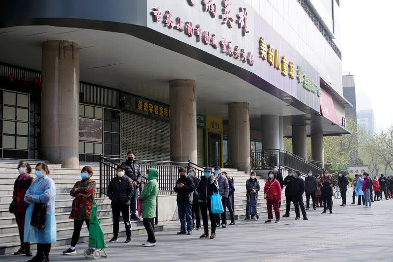 People wearing face masks line up to enter a supermarket in Wuhan