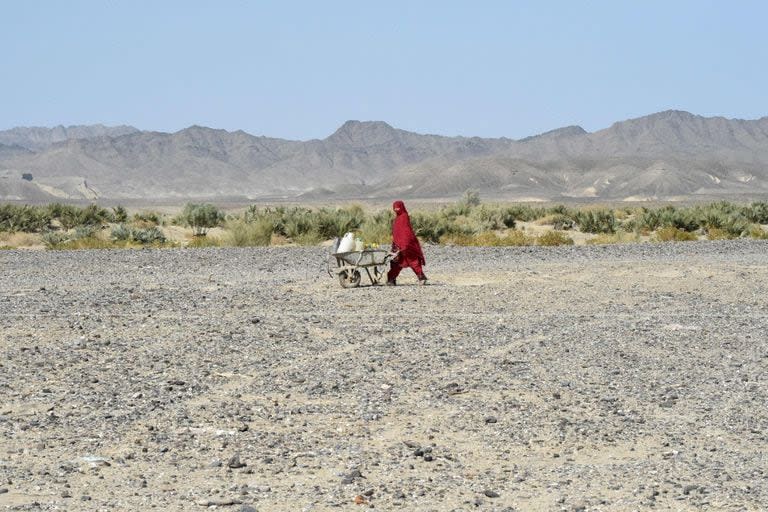 Una mujer lleva latas de agua en una carretilla en la zona de Koh-e-Sabz, en la provincia de Baluchistán, al suroeste de Pakistán, donde Irán lanzó un ataque aéreo, el 18 de enero de 2024. (Banaras KHAN / AFP)