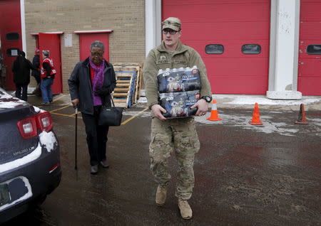 Michigan National Guard Staff Sergeant William Phillips assists a Flint resident with bottled water at a fire station in Flint, Michigan January 13, 2016. REUTERS/Rebecca Cook