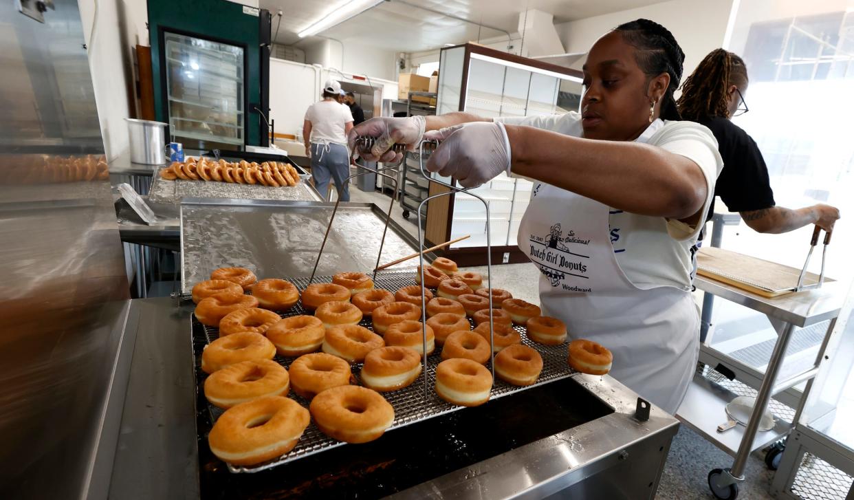 Onica Ashley, 36, of Detroit, pulls up donuts to be coated with a glaze at Dutch Girl Donuts in Detroit on Friday, May 3, 2024.