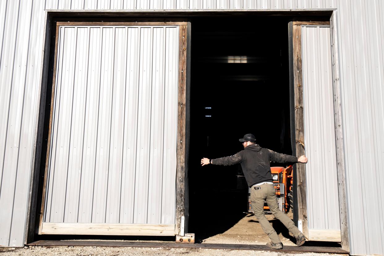 Farm manager Sam Applegate closes a set of barn doors at In Harmony farm on Nov. 30, 2023, in Earlham.