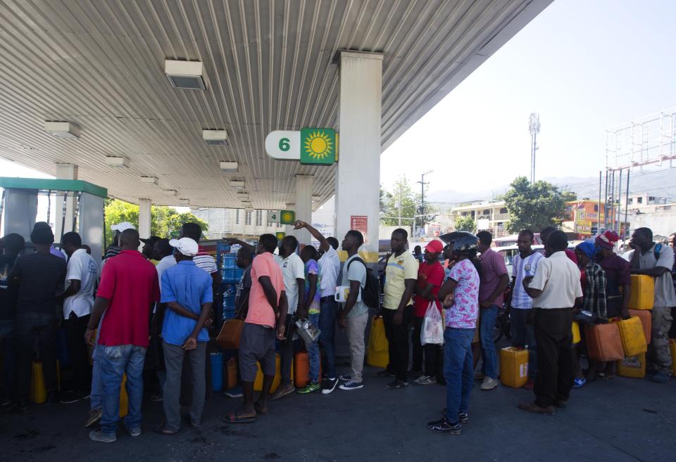 In this April 10, 2019 photo, people line up at a gas station to fill containers with fuel, in Port-au-Prince, Haiti. As Venezuelan President Nicolás Maduro's government has struggled with plunging petroleum production and a cratering economy, the South American country has been forced to stop sending billions in subsidized oil to countries throughout Central America and the Caribbean, including Haiti. (AP Photo/Dieu Nalio Chery)