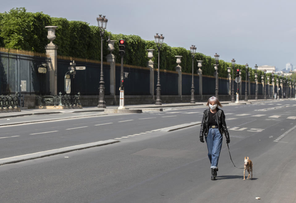 A woman wears a mask to protect against the spread of the coronavirus walks his dog at the empty Rivoli street along the Tuileries Garden in Paris, Saturday, April 25, 2020. France continues to be under an extended stay-at-home order until May 11 in an attempt to slow the spread of the COVID-19 pandemic. (AP Photo/Michel Euler)