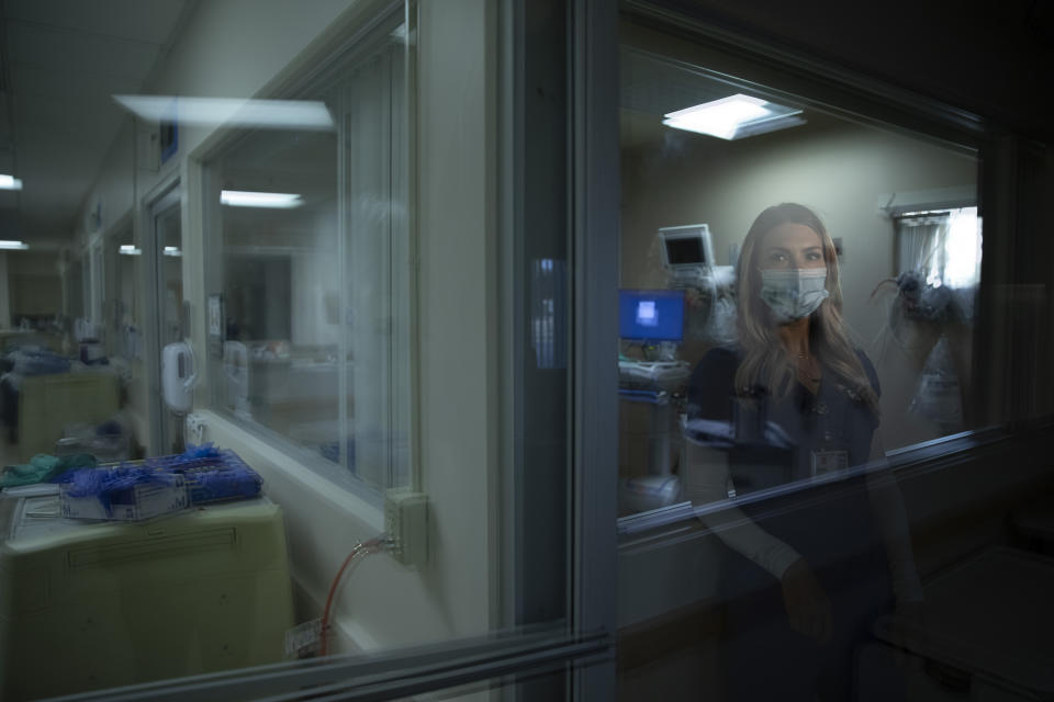 In this photo created with an in-camera multiple exposure, registered nurse Jill Shwam, part of a group of nurses who had been treating coronavirus patients in an intensive care unit, stands for a photo in the empty COVID-19 ICU at Providence Mission Hospital in Mission Viejo, Calif., Tuesday, April 6, 2021. There is a scene that replays in Shwam's head each day: an 11-year-old boy screaming while his mother, in her early 40s, doesn't respond as doctors try to save her. "You need to say goodbye," Shwam remembers saying as the woman's oxygen levels dropped sharply. The woman told her son: "I hope this isn't the last time I talk to you. I have to go." (AP Photo/Jae C. Hong)