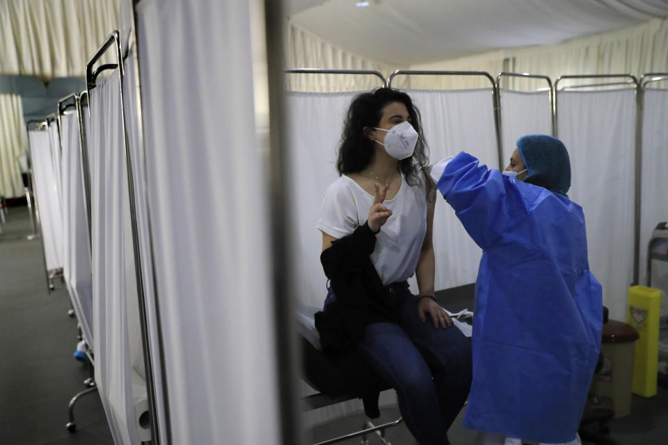 A woman flashes a victory sign as she receives the Pfizer-BioNTech COVID-19 vaccine during a nationwide vaccination campaign, at the Saint George Hospital, in Beirut, Lebanon, Tuesday, Feb. 16, 2021. Lebanon launched its inoculation campaign after receiving the first batch of the vaccine — 28,500 doses from Brussels with more expected to arrive in the coming weeks. (AP Photo/Hussein Malla)