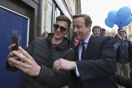 Britain's Prime Minister David Cameron poses for a selfie with a local man as he campaigns in Alnwick, April 13, 2015. REUTERS/Peter Macdiarmird/Pool