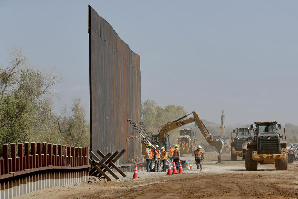 FILE - Government contractors erect a section of the Pentagon-funded border wall along the Colorado River, Sept. 10, 2019, in Yuma, Ariz. Construction of the wall along the U.S.-Mexico border under former President Donald Trump toppled untold numbers of saguaro cactuses in Arizona, put endangered ocelots at risk in Texas and disturbed Native American burial grounds, Congress' official watchdog said Thursday, Sept. 7, 2023. (AP Photo/Matt York, File)