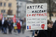 Demonstrators, one of them holding a placard reading : "Beat Macron in retreat, if he does a 49.3, let's make him a 1789 (referring to French revolution) " as they take part to a protest march against plans to push back France's retirement age, in Strasbourg, eastern France, Tuesday, Jan. 31, 2023. Labor unions aimed to mobilize more than 1 million demonstrators in what one veteran left-wing leader described as a "citizens' insurrection." The nationwide strikes and protests were a crucial test both for President Emmanuel Macron's government and its opponents. (AP Photo/Jean Francois Badias)