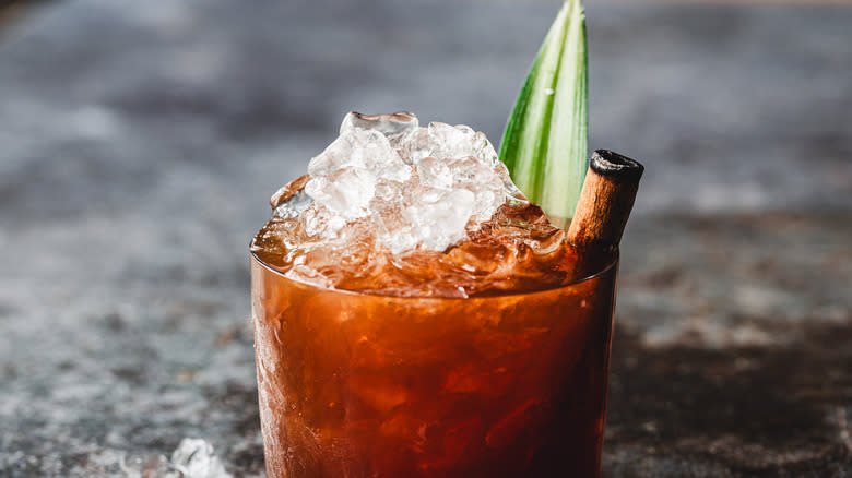 Red cocktail with ice and pineapple leaf