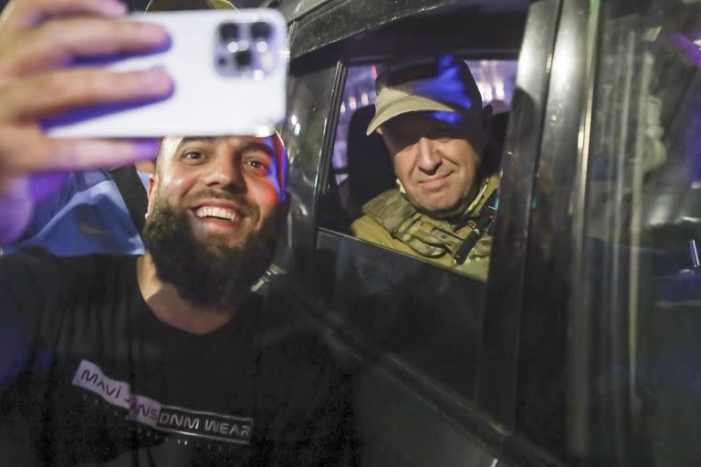 Yevgeny Prigozhin, propietario de la compañía militar Grupo Wagner, a la derecha, se sienta en un vehículo militar y posa para una selfie con un civil en una calle de Rostov en el Don, Rusia,e l sábado 24 de junio de 2023 antes de abandonar una zona del cuartel general del Distrito Militar Sur de Rusia. (AP Foto)