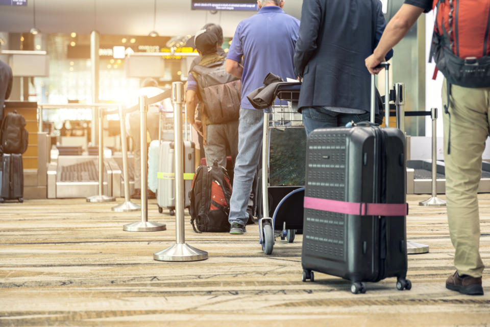 Passengers lined up at the airport to check in their luggage.