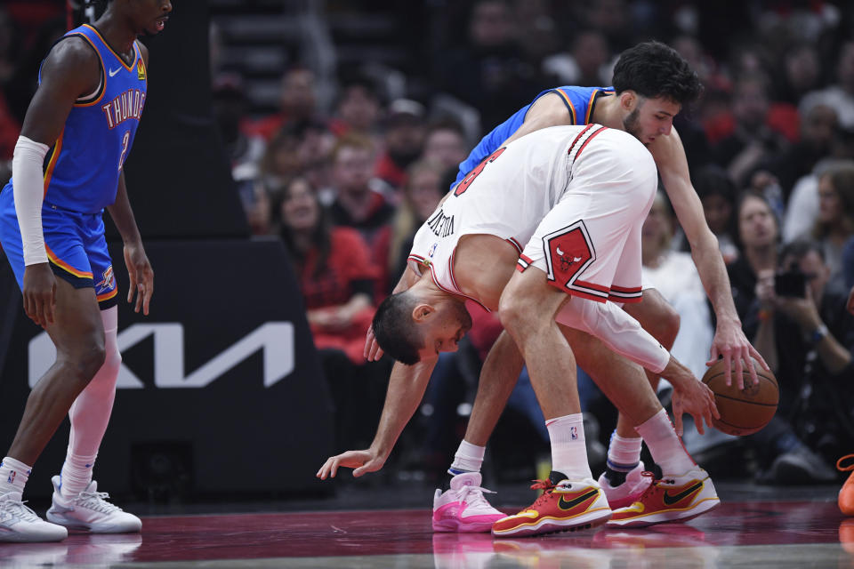 Chicago Bulls' Nikola Vucevic, front right, and Oklahoma City Thunder's Chet Holmgren reach for the ball during the first half of an NBA basketball game Wednesday, Oct. 25, 2023, in Chicago. (AP Photo/Paul Beaty)