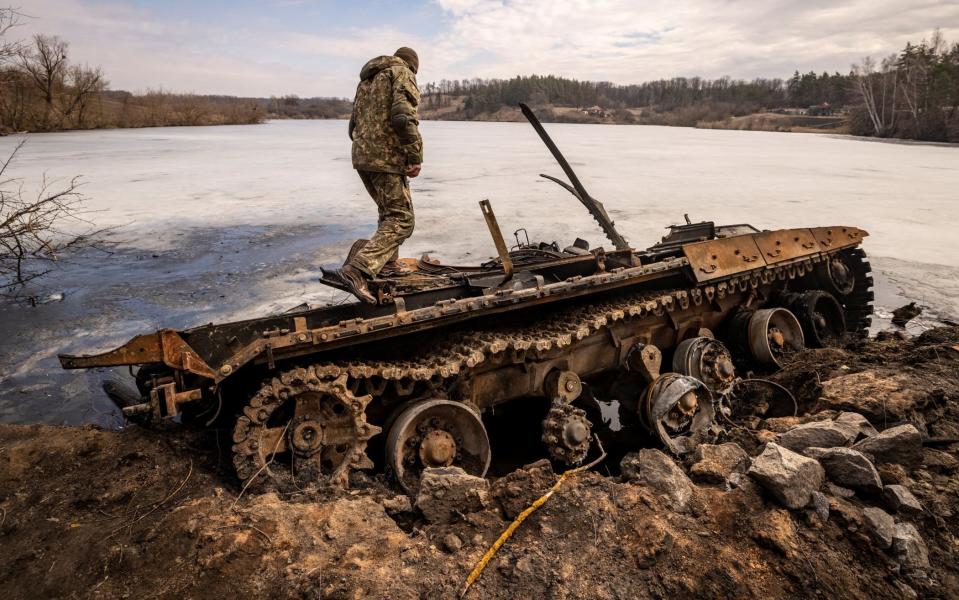 Ukrainian serviceman stands near a destroyed Russian tank in the northeastern city of Trostyanets on March 29, 2022