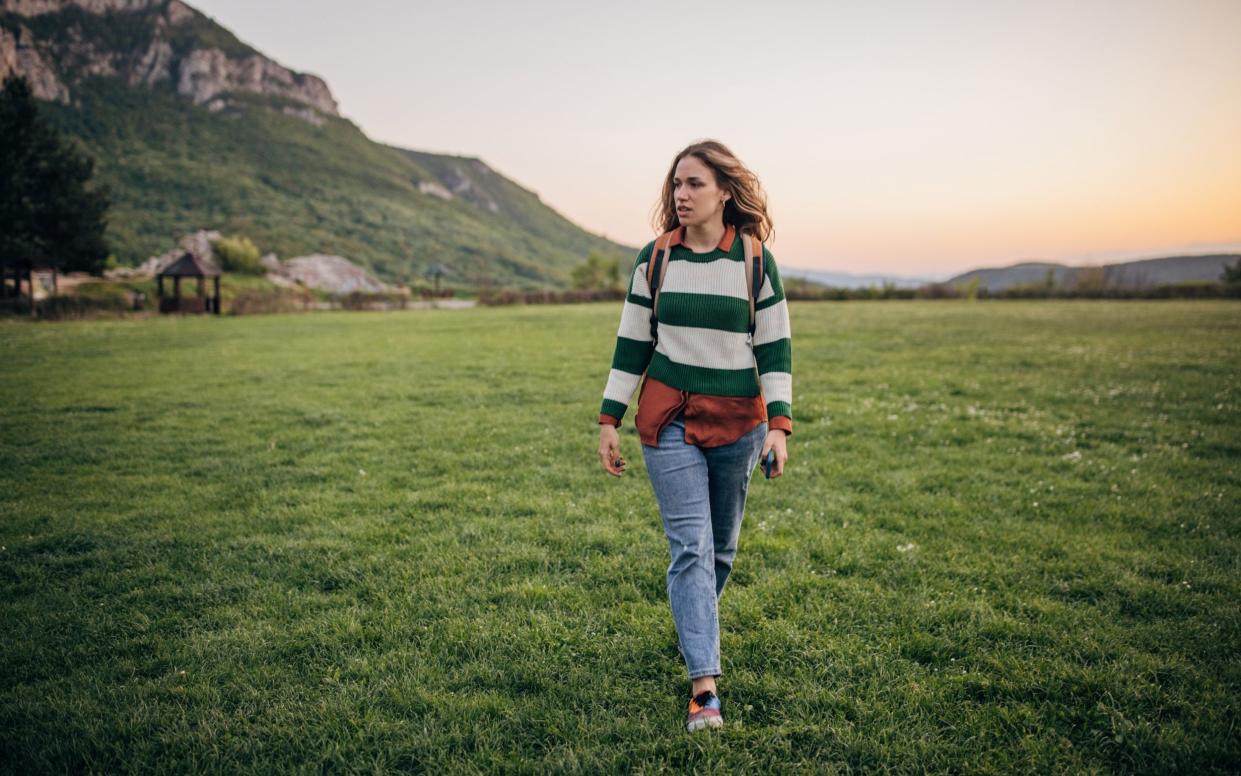 A hiker walks through a field at sunset