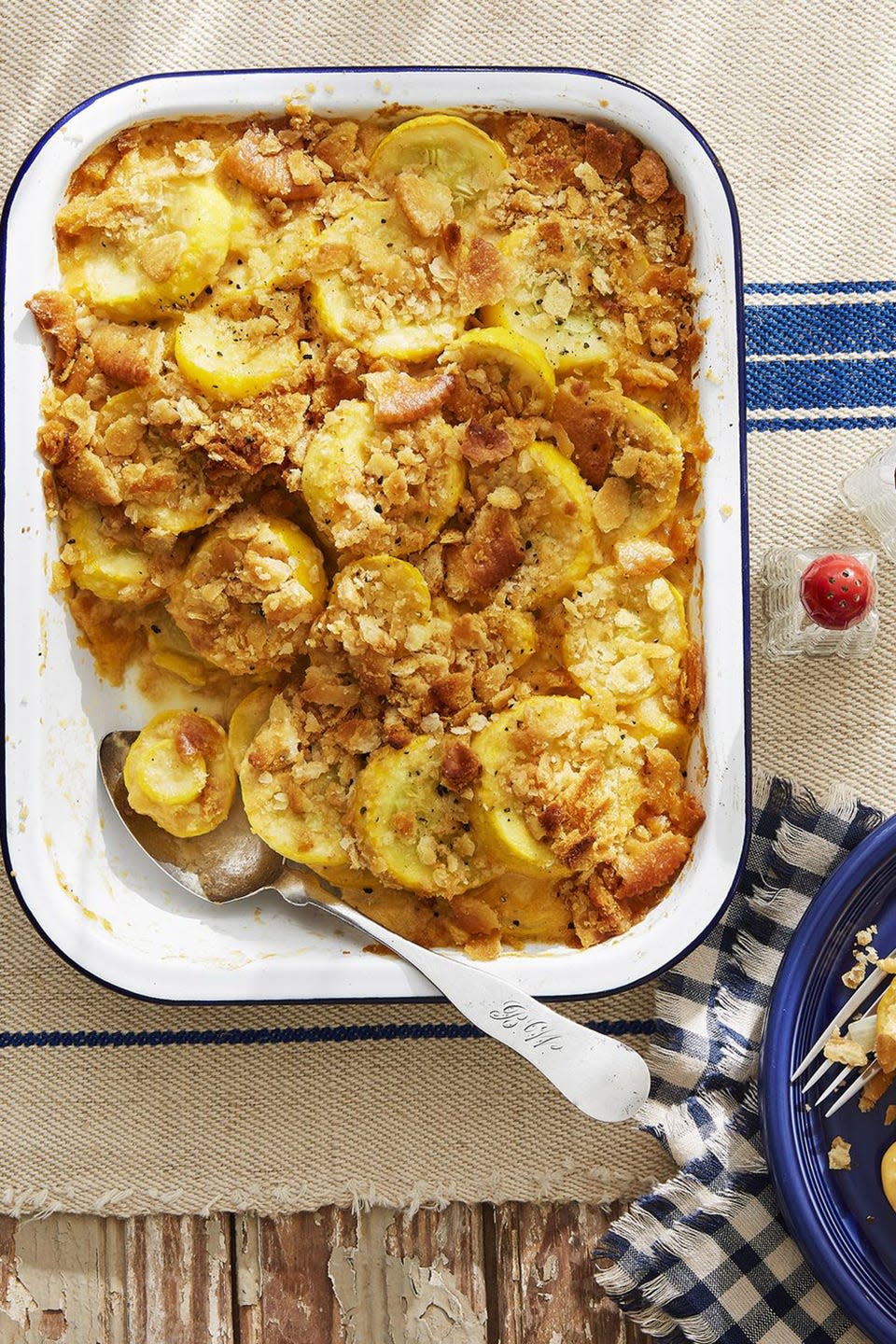 squash casserole in a white rectangle baking dish with a serving spoon