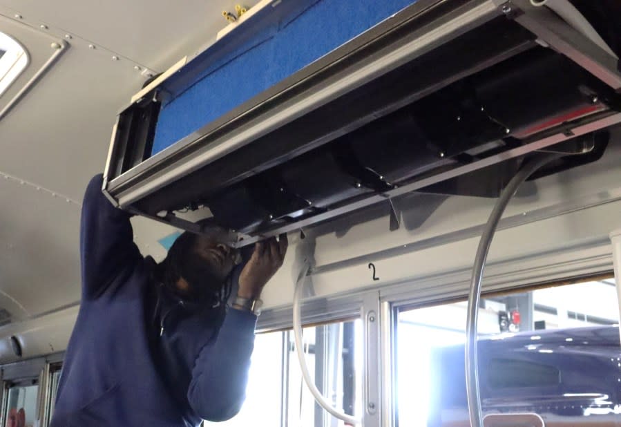 A technician installs an air conditioning unit on a Lafayette Parish School bus, as part of a new initiative with Kenworth of Louisiana – Lafayette.