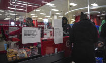 An associate, left, ring customer purchases at a Target store, Tuesday Oct. 20, 2020, in New York. The coronavirus pandemic is transforming holiday hiring this year, with companies starting hiring earlier and offering extra safety protocols. Target said it expects to hire more than 100,000 people for the holiday season. (AP Photo/Bebeto Matthews)