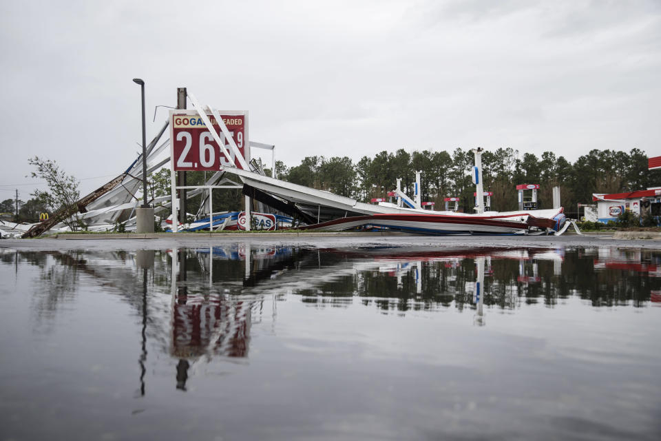 A damaged gas station is reflected in a puddle in Wilmington, North Carolina.