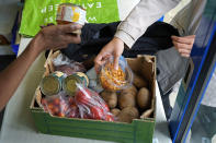 A woman, right, collects food at the Community Food Hub in Hackney, London, Thursday, June 13, 2024. Since calling a general election, British Prime Minister Rishi Sunak has been at pains to repeat a key message on the campaign trail: The economy is turning a corner, inflation is down, and things are looking up. That’s not the reality for millions across the U.K. still feeling the squeeze from high food, energy and housing prices. (AP Photo/Kin Cheung)