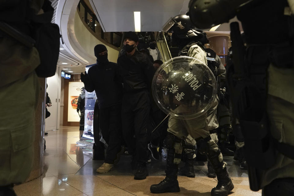 Riot police take away protesters in a mall during a rally on Christmas Eve in Hong Kong on Tuesday, Dec. 24, 2019. More than six months of protests have beset the city with frequent confrontations between protesters and police. (AP Photo/Kin Cheung)