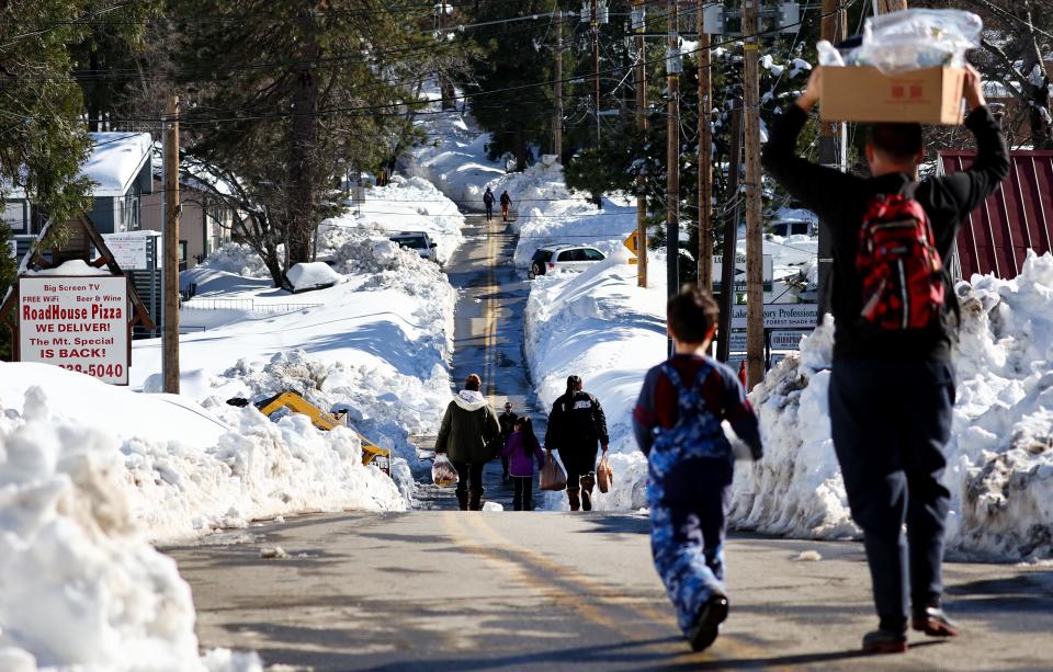 People carry donated food after a series of winter storms dumped heavy snowfall in the San Bernardino Mountains in Southern California on March 3, 2023 in Crestline, California.