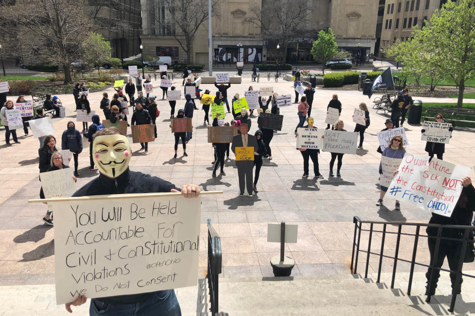 FILE - In this April 9, 2020 file photo, about 75 people wearing masks and carrying signs protest outside the Ohio Statehouse on Thursday, April 9, 2020, in Columbus, Ohio. A plot to kidnap Michigan’s governor has put a focus on the security of governors who have faced protests and threats over their handling of the coronavirus pandemic. The threats have come from people who oppose business closures and restrictions on social gatherings. (AP Photo/Andrew Welsh-Huggins)