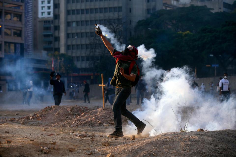 A demonstrator returns teargas to Bolivarian National Police during clashes in Caracas, Venezuela, Wednesday, March 5, 2014. The one year anniversary of the death of Venezuela's former President Hugo Chavez was marked with a mix of street protests and solemn commemorations that reflected deep divisions over the Venezuela he left behind. (AP Photo/Fernando Llano)