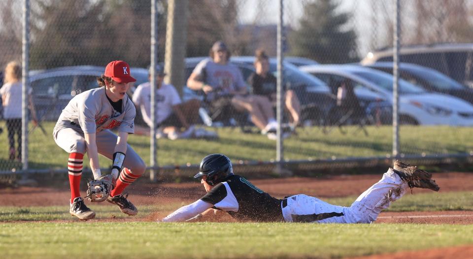 Aurora junior Ben Schecterman slides into third base as Kent Roosevelt junior third baseman Logan Poole goes for the tag during Tuesday night’s game at Aurora High School.