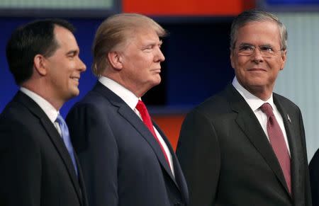 Republican 2016 presidential candidate and former Florida Governor Jeb Bush (R) looks over at businessman Donald Trump (C) and Wisconsin Governor Scott Walker (L) as the candidates pose with seven other candidates at the first official Republican presidential candidates debate of the 2016 U.S. presidential campaign in Cleveland, Ohio, August 6, 2015. REUTERS/Brian Snyder