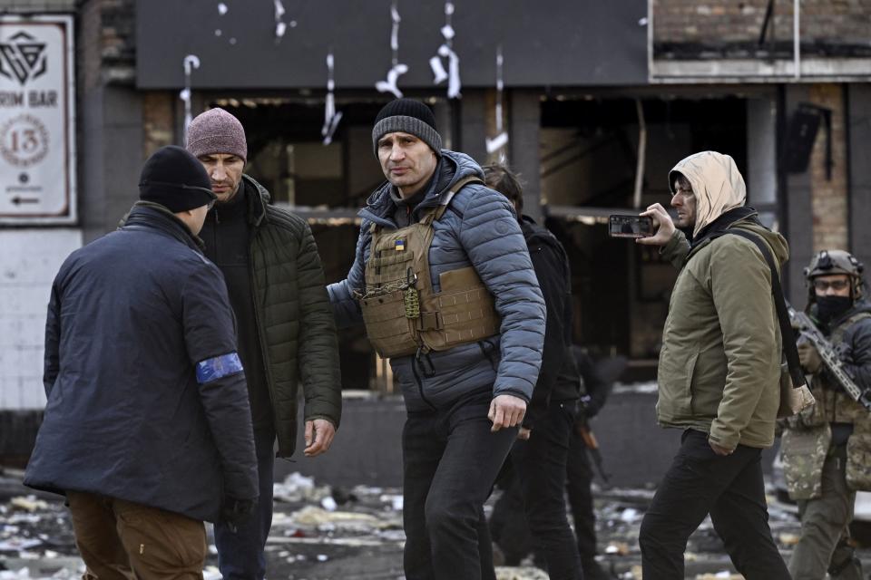 Kyiv's mayor Vitali Klitschko (C) walks next to his brother Wladimir (2nd-L)  in front of a destroyed apartment building, in Kyiv on March 14, 2022, as various neighbourhoods of the Ukraine capital Kyiv came under shelling and missile attacks, city officials said, on the 19th day of the Russian invasion of Ukraine. - Ukrainian Prime Minister Denys Chmygal asked the Council of Europe on March 14, 2022 for the 