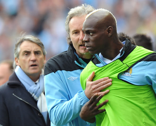 Manchester City's Italian striker Mario Balotelli (R) is restrained as Joey Barton (not pictured) leaves the field during the English Premier League football match between Manchester City and Queens Park Rangers at The Etihad stadium in Manchester, north-west England on May 13, 2012. AFP PHOTO/PAUL ELLIS RESTRICTED TO EDITORIAL USE. No use with unauthorized audio, video, data, fixture lists, club/league logos or 'live' services. Online in-match use limited to 45 images, no video emulation. No use in betting, games or single club/league/player publications.PAUL ELLIS/AFP/GettyImages