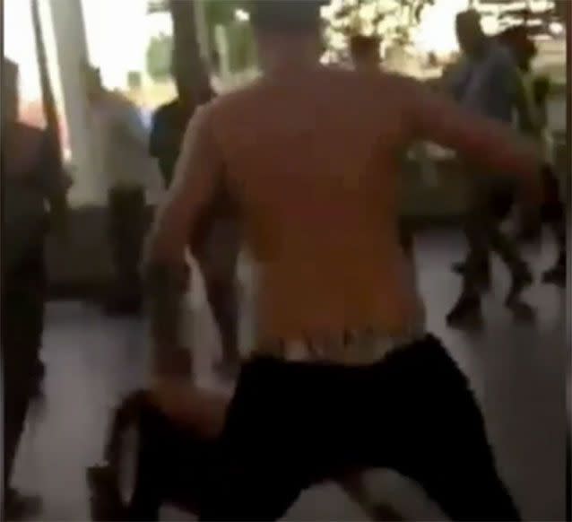 A shirtless young man puts up his dukes and fights other youths on the street